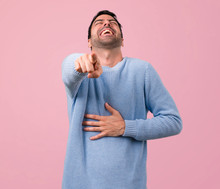 Handsome Man Pointing With Finger At Someone And Laughing A Lot On Pink Background