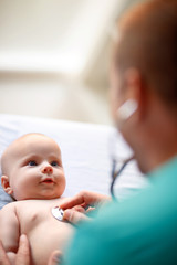 Wall Mural - Baby looking at doctor on checkup with stethoscope