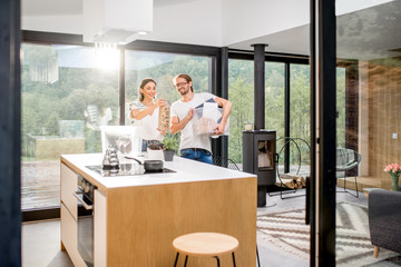 Young and happy couple unpacking different home stuff making order in their new and modern house