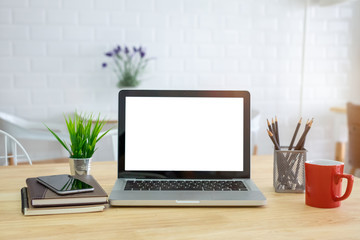 A note book, laptop, mouse, coffee cup, pen, graph paper(document) on the office desk(table) behind white blind.