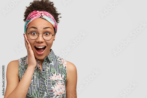 Fotografía Joyful amazed dark skinned female keeps mouth opened, expresses surprisement and