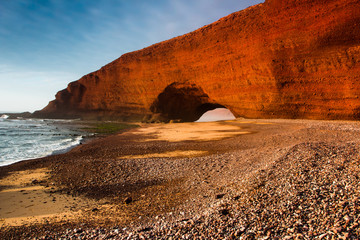 Sunset in Legzira dramatic huge red natural stone arches reaching over the sea. Atlantic Ocean, Morocco, Sidi Ifni