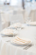 Festive table setting at a banquet in white. White plates, napkins and tablecloth in a restaurant
