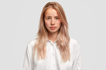 Sticker - Headshot of self assured Caucasian female with healthy pure skin, wears loose white shirt, looks directly into camera, has serious expression, contemplates about future plans. Beauty and lifestyle