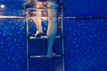 Men's Legs On The Stairs Underwater In The Swimming Pool In Summer