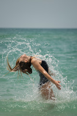 Wall Mural - Beautiful young girl splashing in the sea