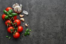 Food Background. Flat Lay Of Fresh Tomatoes With Basil, Garlic And Seasalt On Black Stone Background. Top View With Copy Space On The Right.