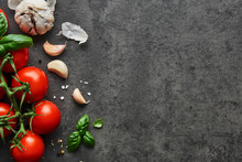 Food Background. Flat Lay Of Fresh Tomatoes With Basil, Garlic And Seasalt On Black Stone Background. Top View With Copy Space.