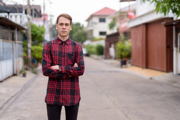 Wall Mural - Young handsome man wearing red checkered shirt in the streets ou