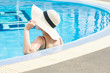 © Suphansa - Women wearing straw hats and relax in the swimming pool.
