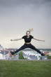 © KONSTANTIN SHISHKIN - Young caucasian girl performs twine jumping over background cityscape
