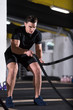 © .shock - athlete man doing battle ropes cross fitness exercise