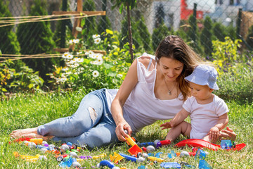 Wall Mural - Young mother and her boy, playing in garden with colorful construction