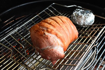 Roast pork cooking on a barbecue over charcoal