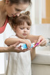 © Oksana Kuzmina - Mom puts toothpaste on a child brush, brushing teeth