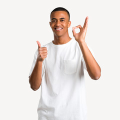 Young african american man showing an ok sign with fingers and giving a thumb up gesture with the other hand on isolated background