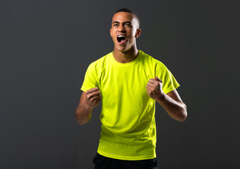 Wall Mural - Soccer player man with dark skinned playing celebrating victory on dark background