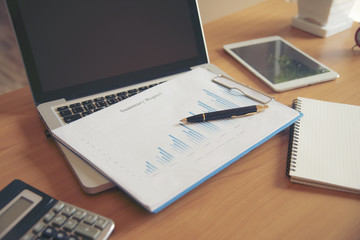 Laptop with financial documents on wooden table