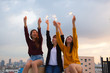 © sorrapongs - Asian group of friends lighting sparklers and enjoying freedom at sunset,asian woman holding sparklers happily on rooftop