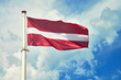 National flag of Latvia on flagpole against cloudy sky