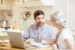 © pressmaster - Young man and woman sitting by table in the kitchen, discussing working points and preparing business presentation