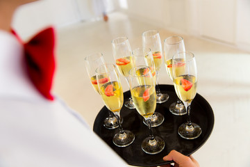 Wall Mural - Waiter With Red Bow Standing With Champagne Glasses And Strawberries