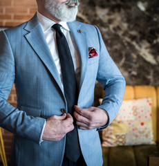 Man in expensive custom tailored suit standing and posing indoors