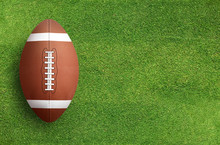 American Football Ball On Grass Field Background. Football Ball 3D Illustration.