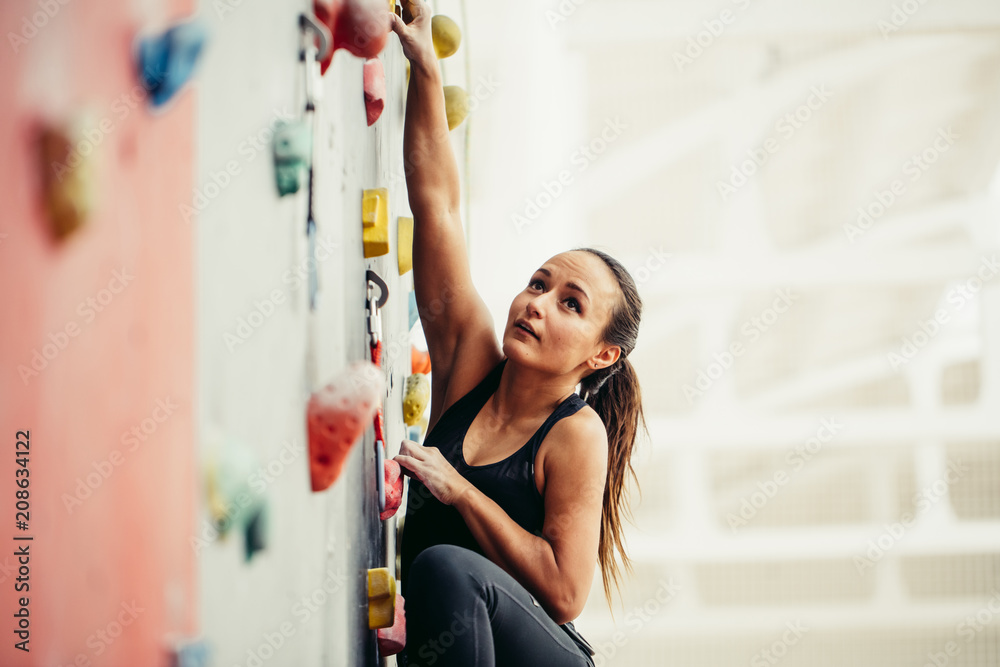 Cropped view of fit business woman, climbing on atrificial rock in fitness, reaching new heights in business and sport. white background with copyspace - obrazy, fototapety, plakaty 