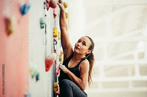 Cuadros en Lienzo Cropped view of fit business woman, climbing on atrificial rock in fitness, reaching new heights in business and sport