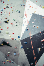 Grey Surface Of An Artificial Rock Climbing Wall With Toe And Hand Handles And Hooks Studs.