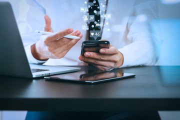 Poster - close up of businessman working with smart phone on wooden desk in modern office with virtual icon diagram with glass reflected view