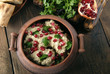 Satsivi with pomegranate seeds and cilantro is traditional georgian food. The Georgian dishes on a wooden background