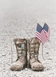 Old military combat boots with dog tags and two small American flags. Rocky gravel background with copy space. Memorial Day or Veterans day concept. Vintage tone.