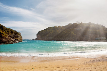 Poster - Beautiful sandy beach with sunbeam at Paleokastritsa in Corfu, Greece