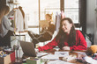 © Yakobchuk Olena - Positive girl typing in laptop while sitting at table during labor. She talking with comrades while they having job with clothes