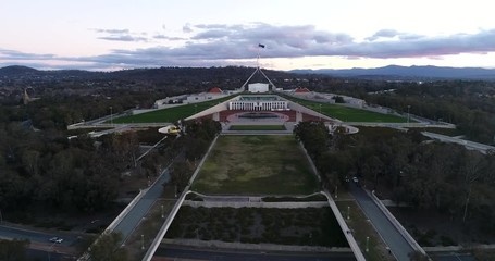 Wall Mural - Facade of Australian parliament house on capitol hill in Canberra at sunset time with waving flag on tall flagpole over masts.
