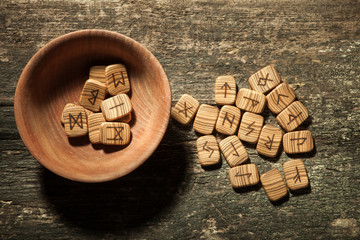 Runes in a wooden plate on a textured old textured wooden surface