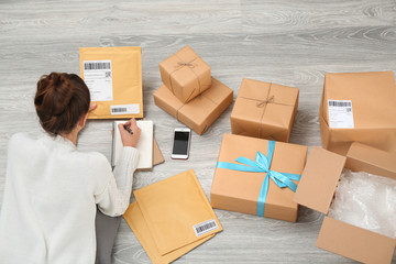 Woman preparing parcels for shipment to customer on floor