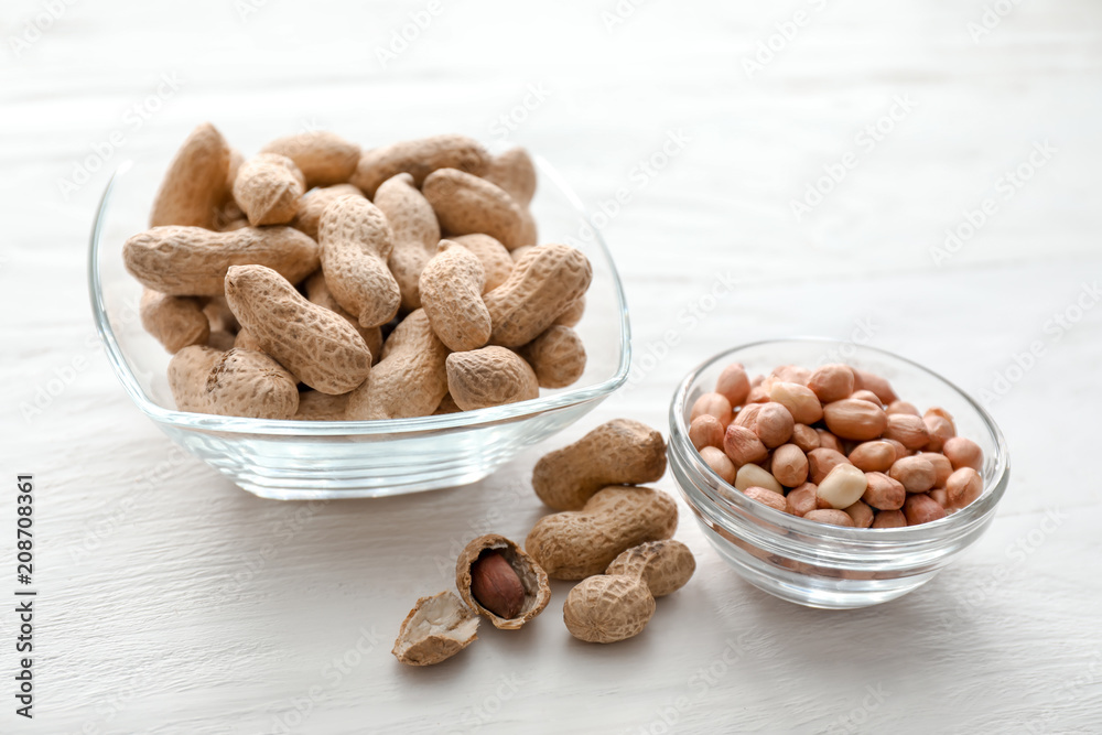 Bowls with tasty peanuts on wooden table