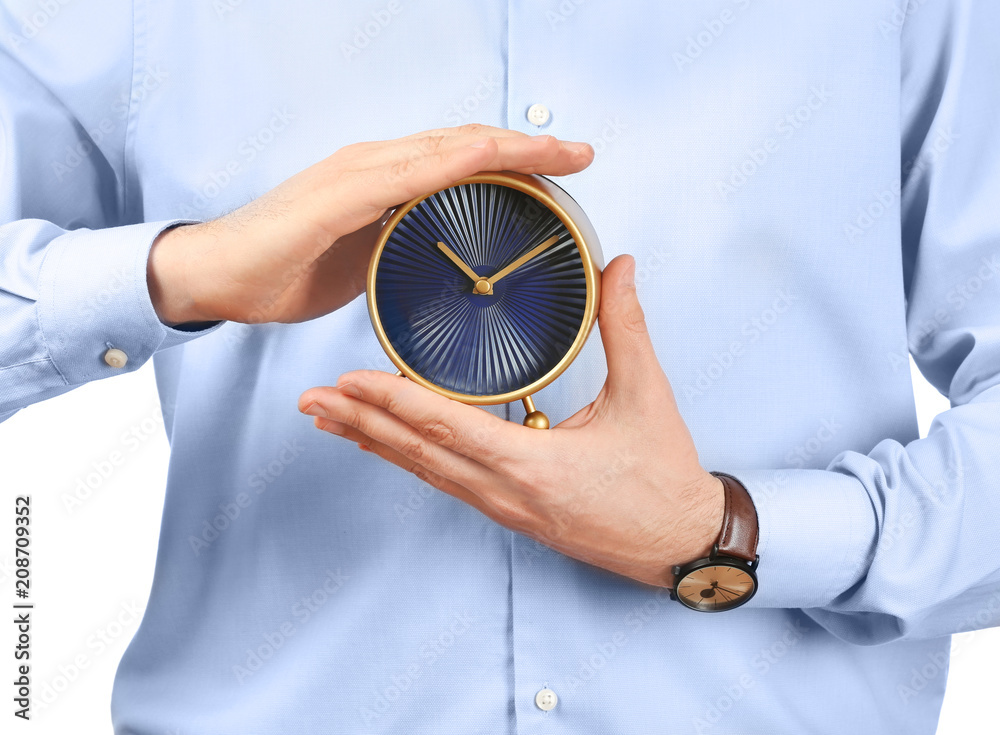 Young businessman holding alarm clock on white background