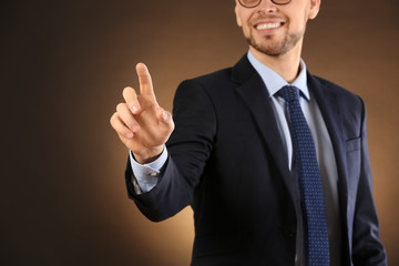 Poster - Young businessman using virtual screen on color background