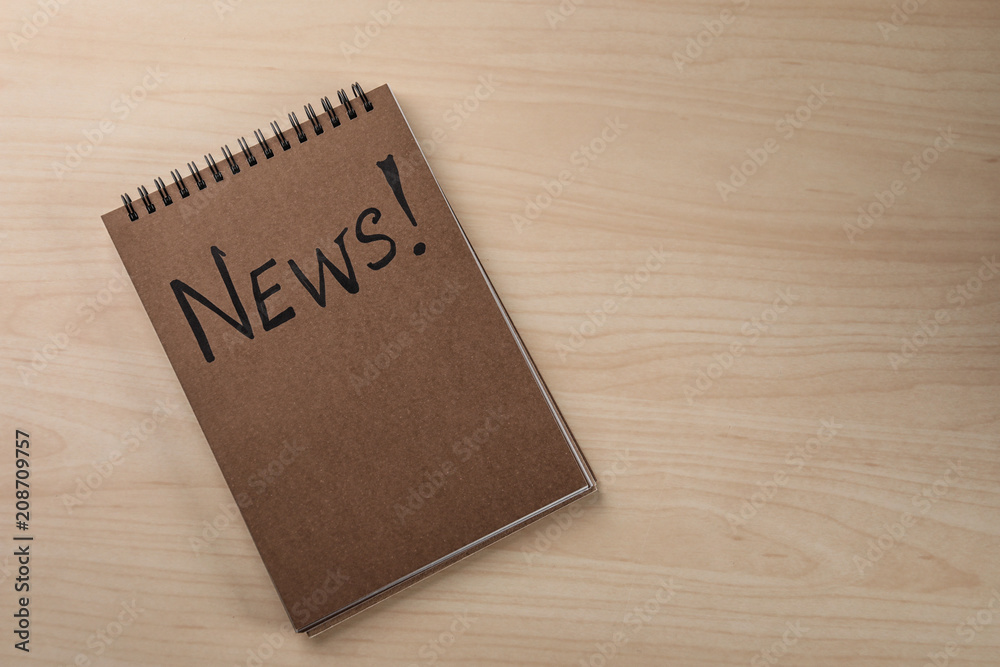 Notebook with word NEWS on wooden background