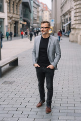 Wall Mural - Mature professional man standing in urban scene