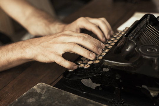 Young man's hands typing on an antique vintage typewriter