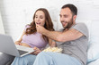 © Viacheslav Yakobchuk - Open mouth honey. Jolly man giving popcorn to pregnant woman and watching movie