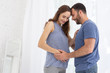 © Viacheslav Yakobchuk - Future together. Low angle of jolly pregnant woman and man smiling and touching tummy