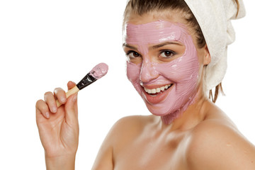 young smiling woman posing with  facial mask on her face with a towel on her head