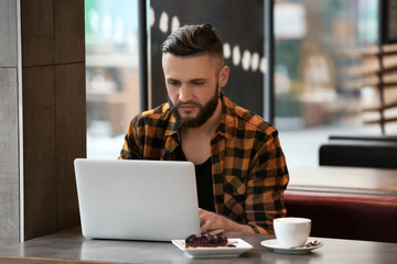 Wall Mural - Young freelancer with laptop working in cafe