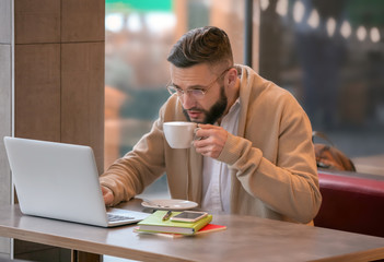 Canvas Print - young freelancer with cup of coffee and laptop working in cafe